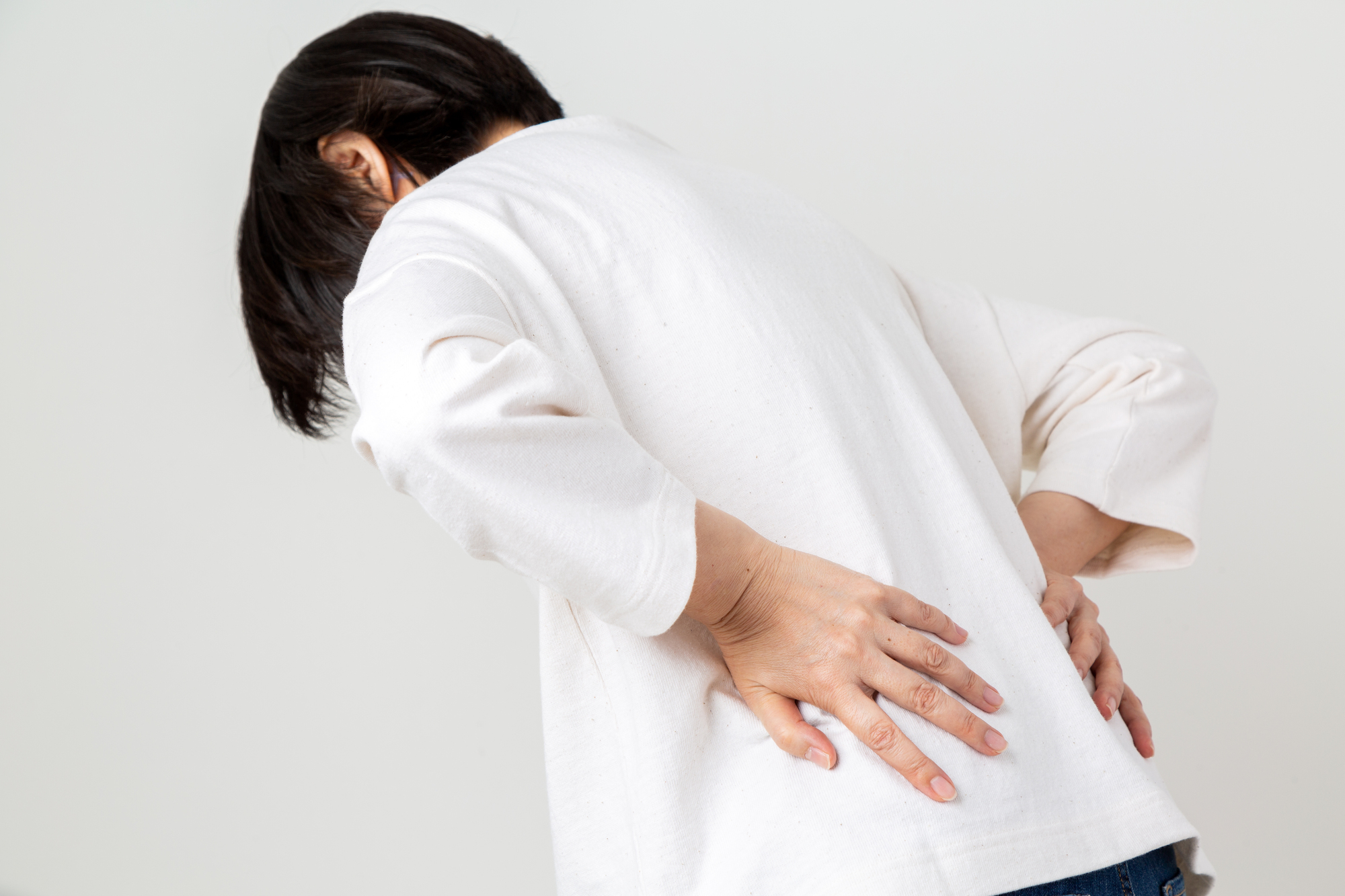 前かがみで腰を押さえる女性