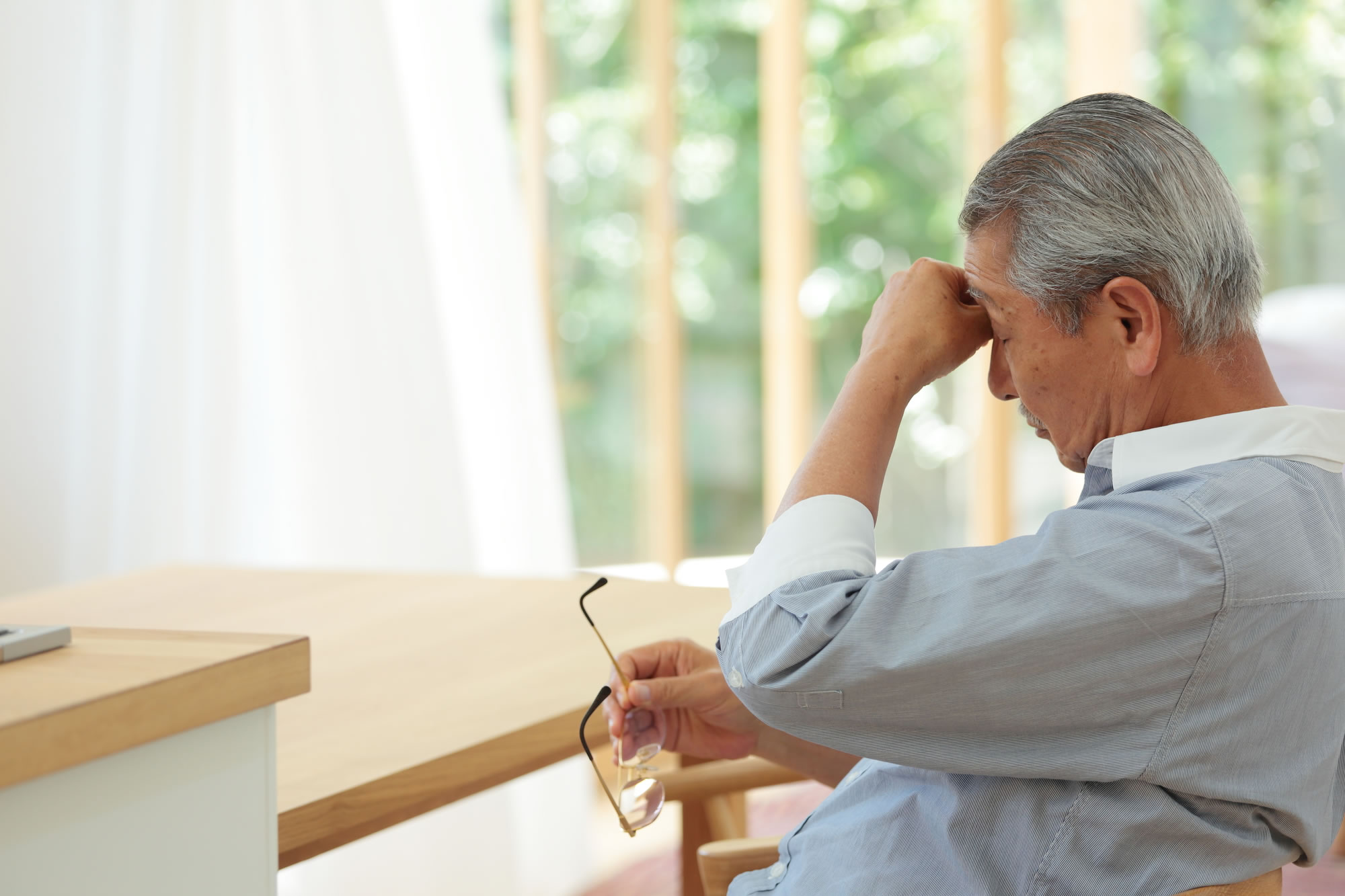 目の疲れから目頭を押さえている男性