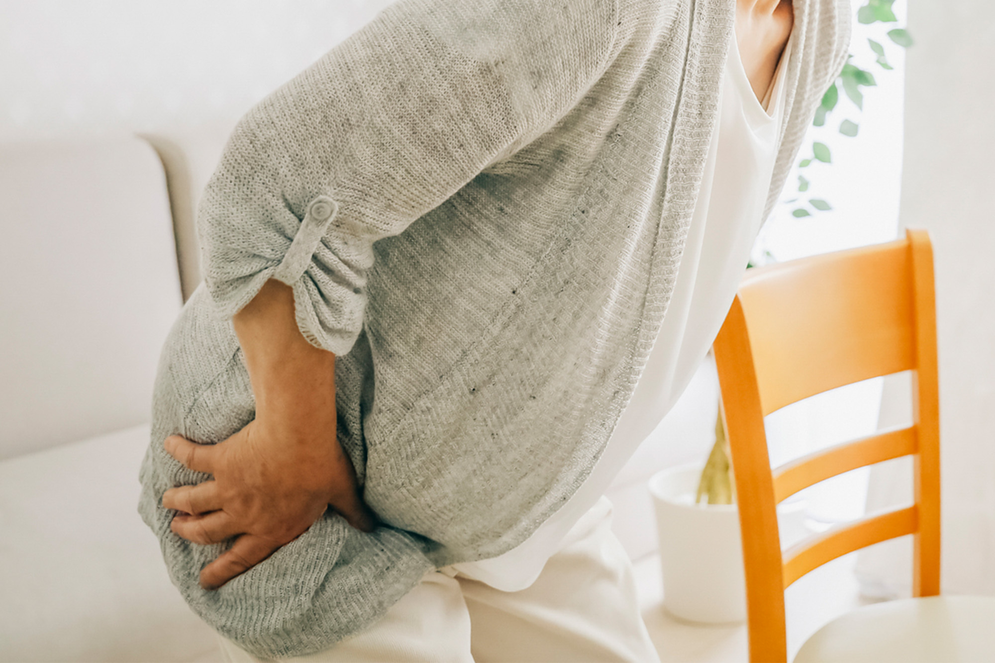 股関節の痛みで辛そうに股関節を押さえている様子