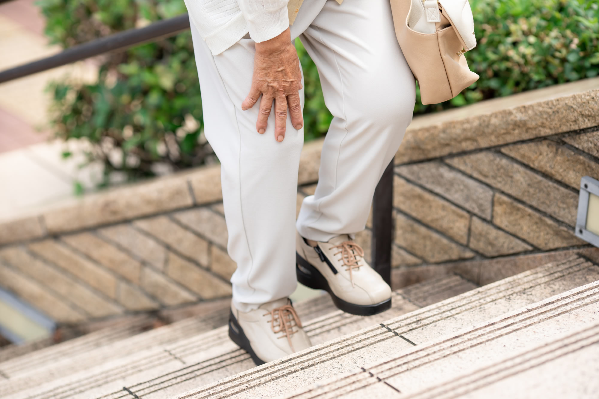 膝の関節痛で階段を上るのがつらい様子