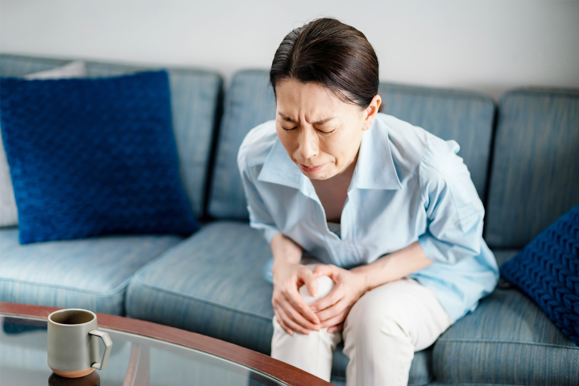 関節痛による膝の痛みで辛そうにしている女性