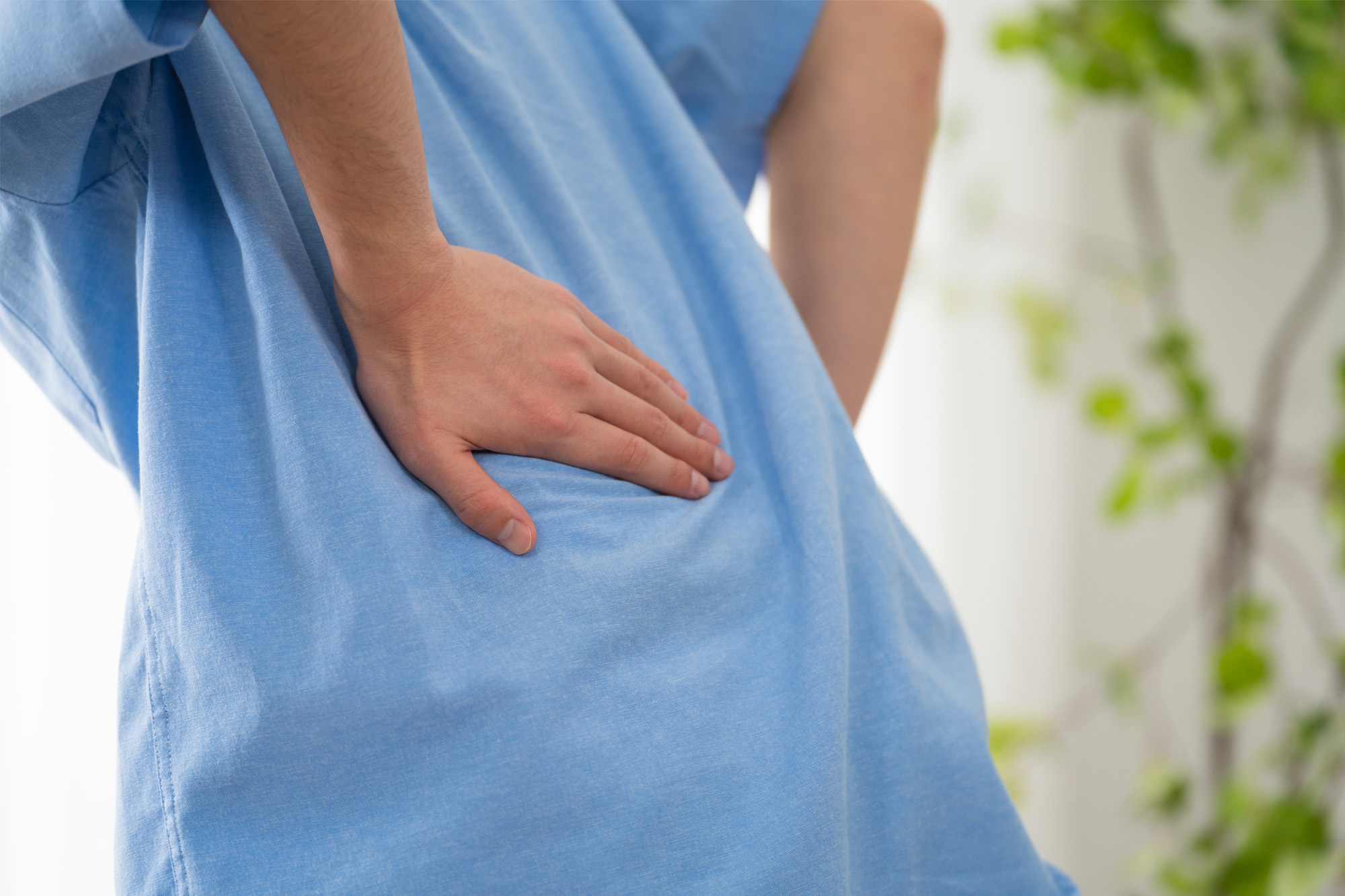 脊柱に痛みを感じて腰部を押さえる様子