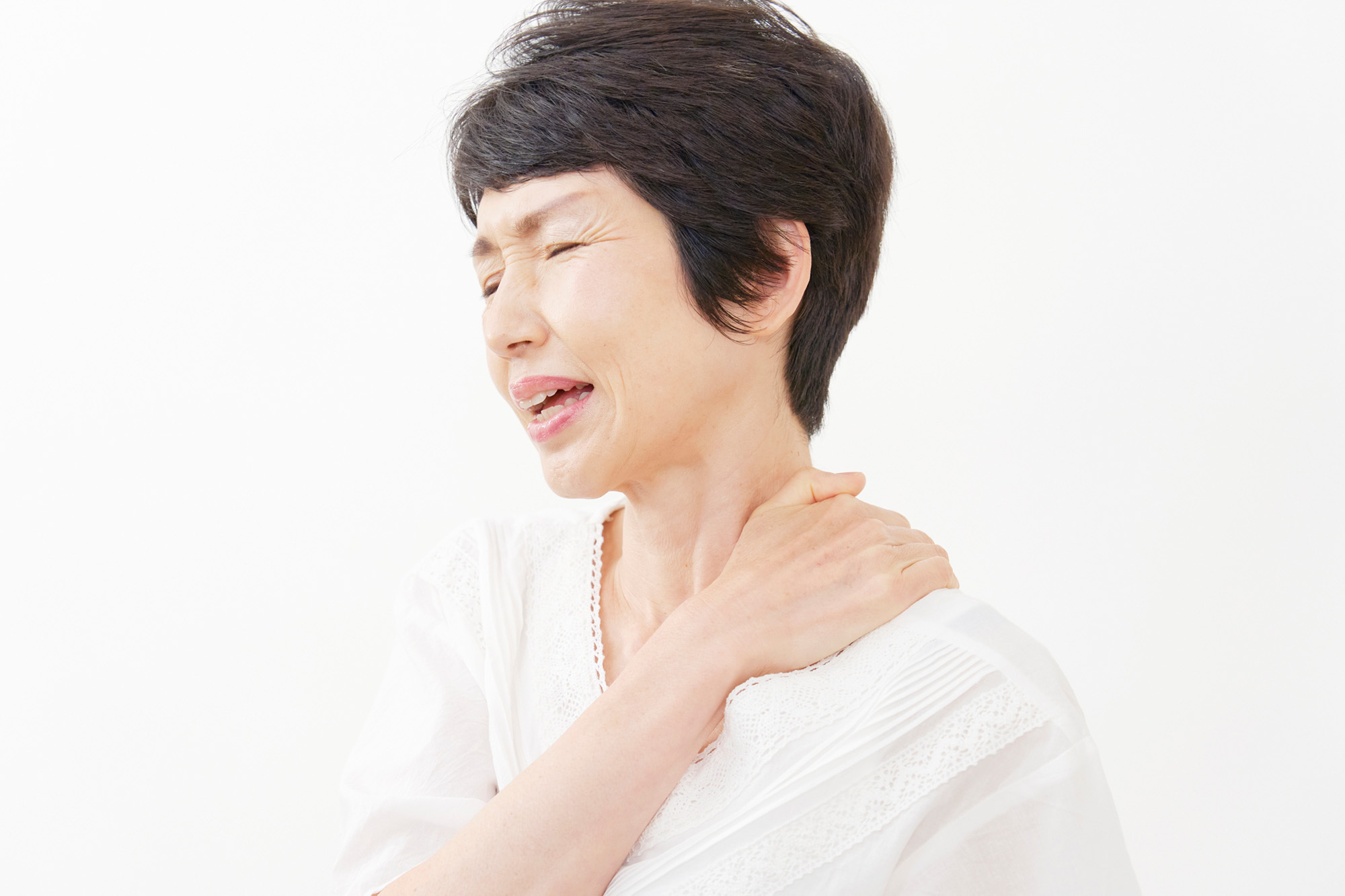 つらそうに肩を押さえる女性