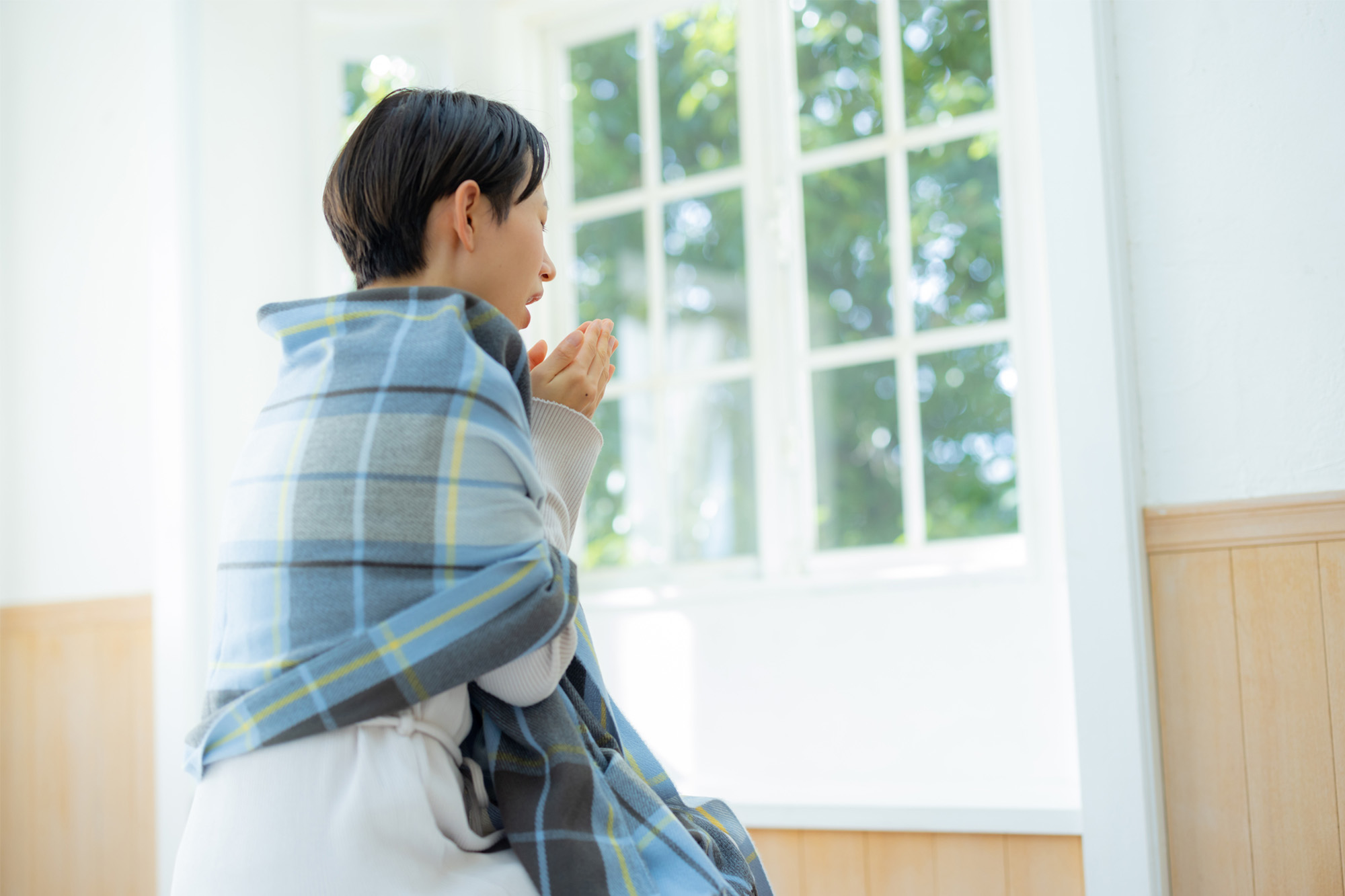 冷えを感じて、手を温める女性