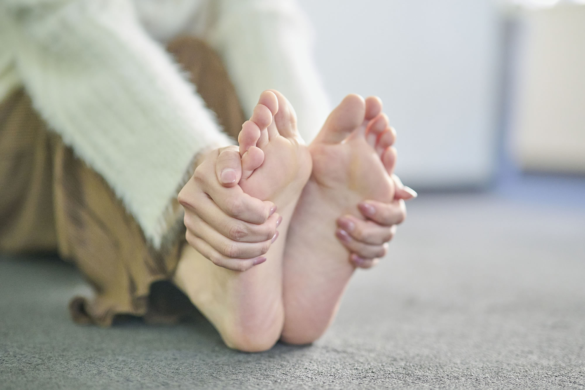 末端冷え性で足先を抑える女性