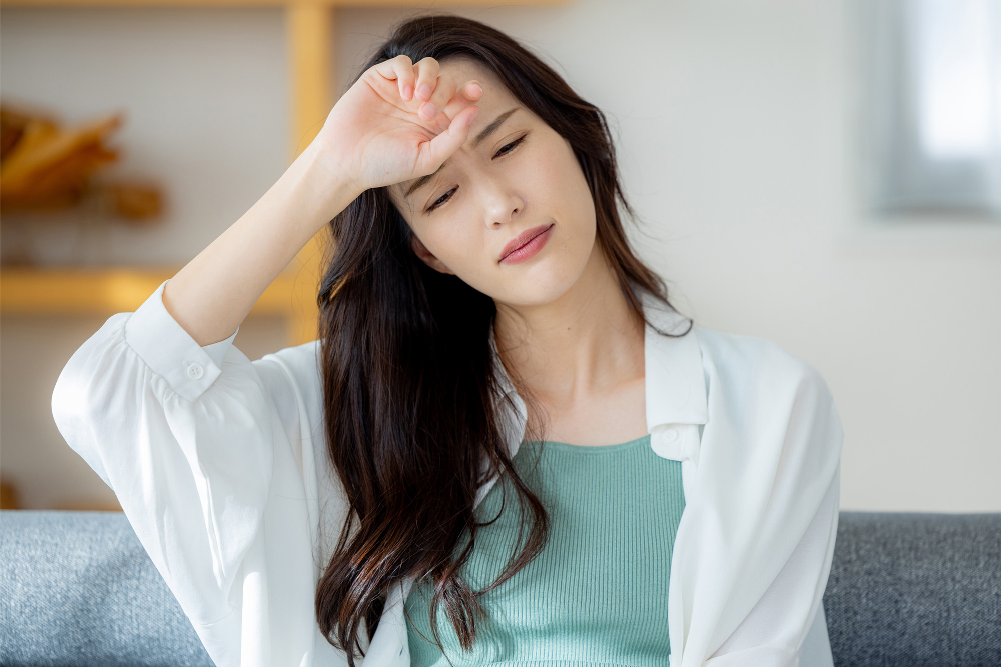 更年期のめまいによる不調で額を押さえる女性