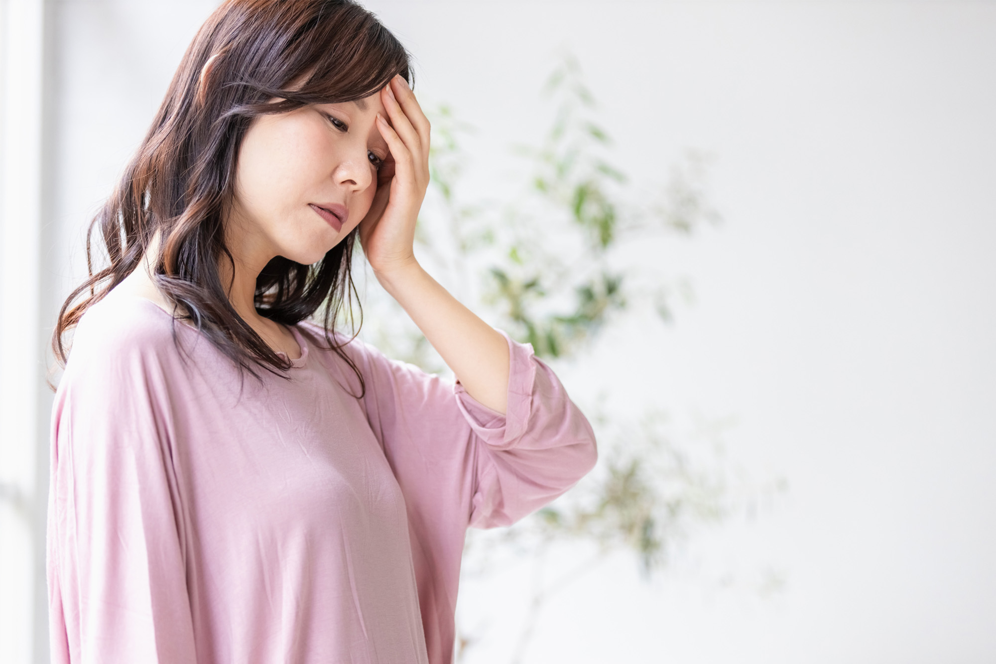 めまいで頭を押さえる女性