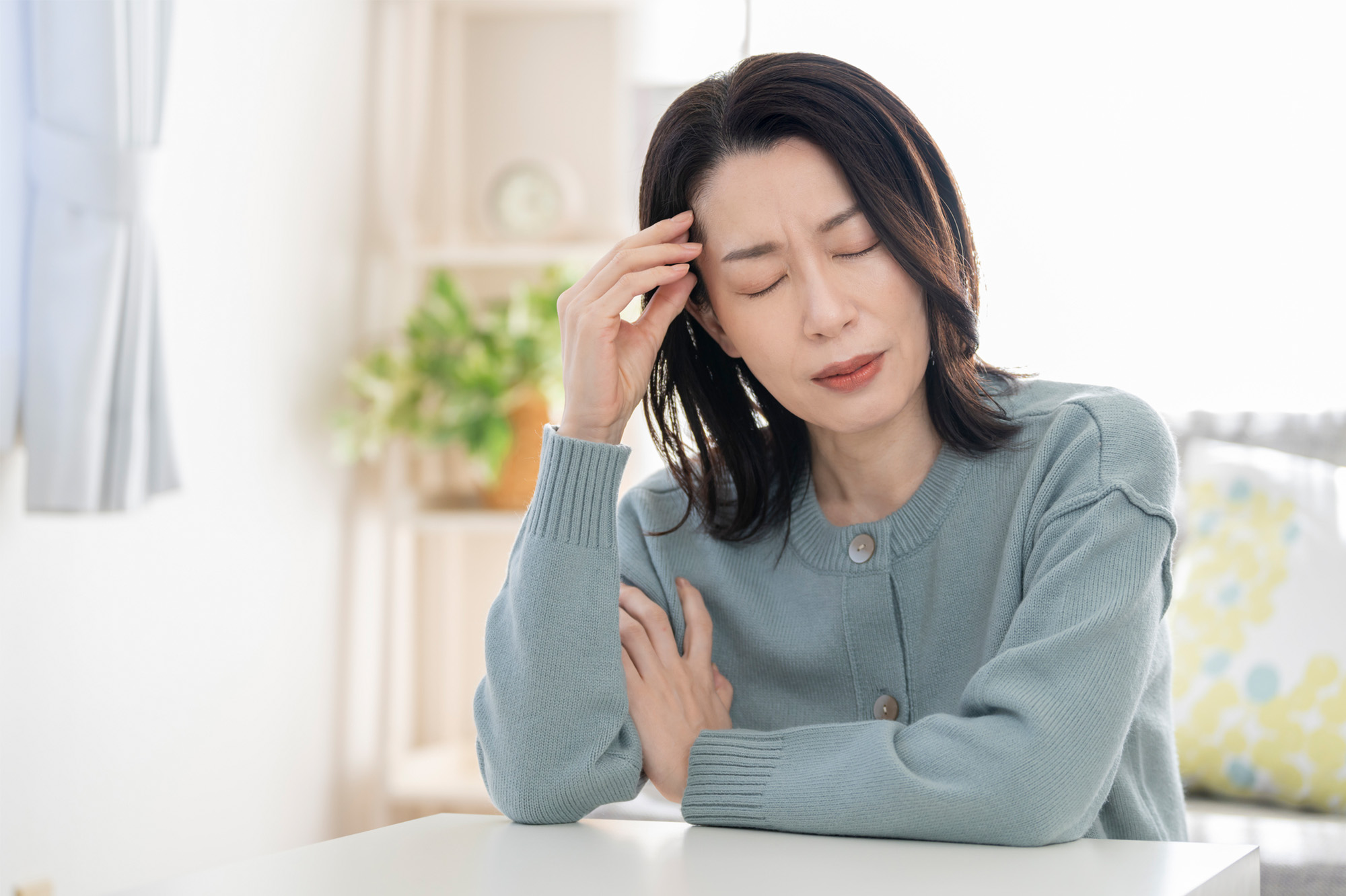 更年期障害による頭痛で辛そうにする女性