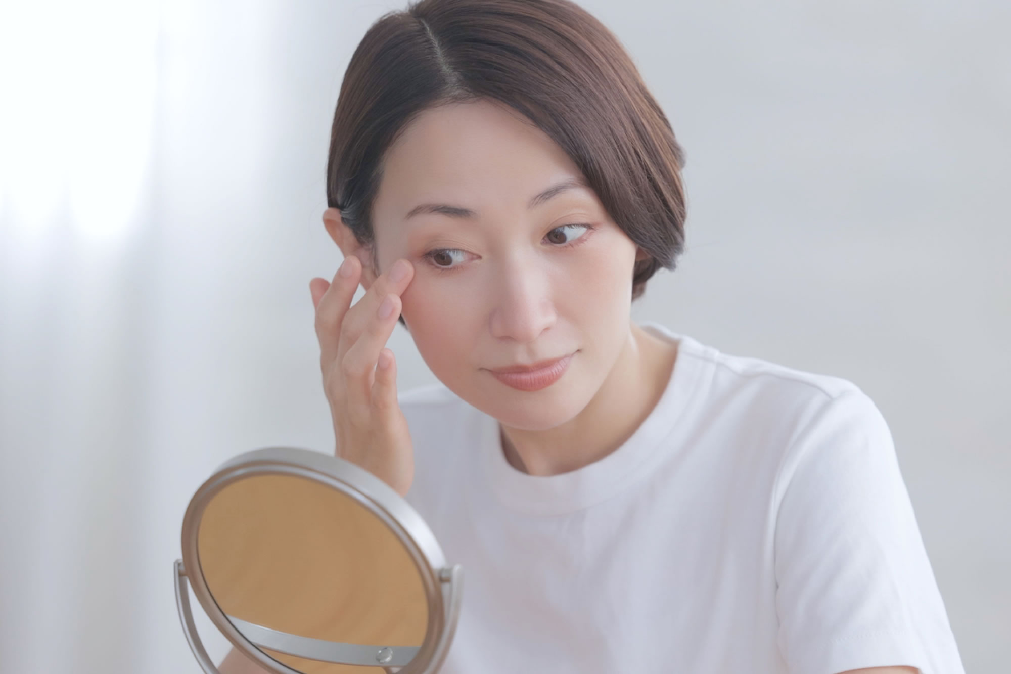 鏡を見て肌のシミに悩む女性