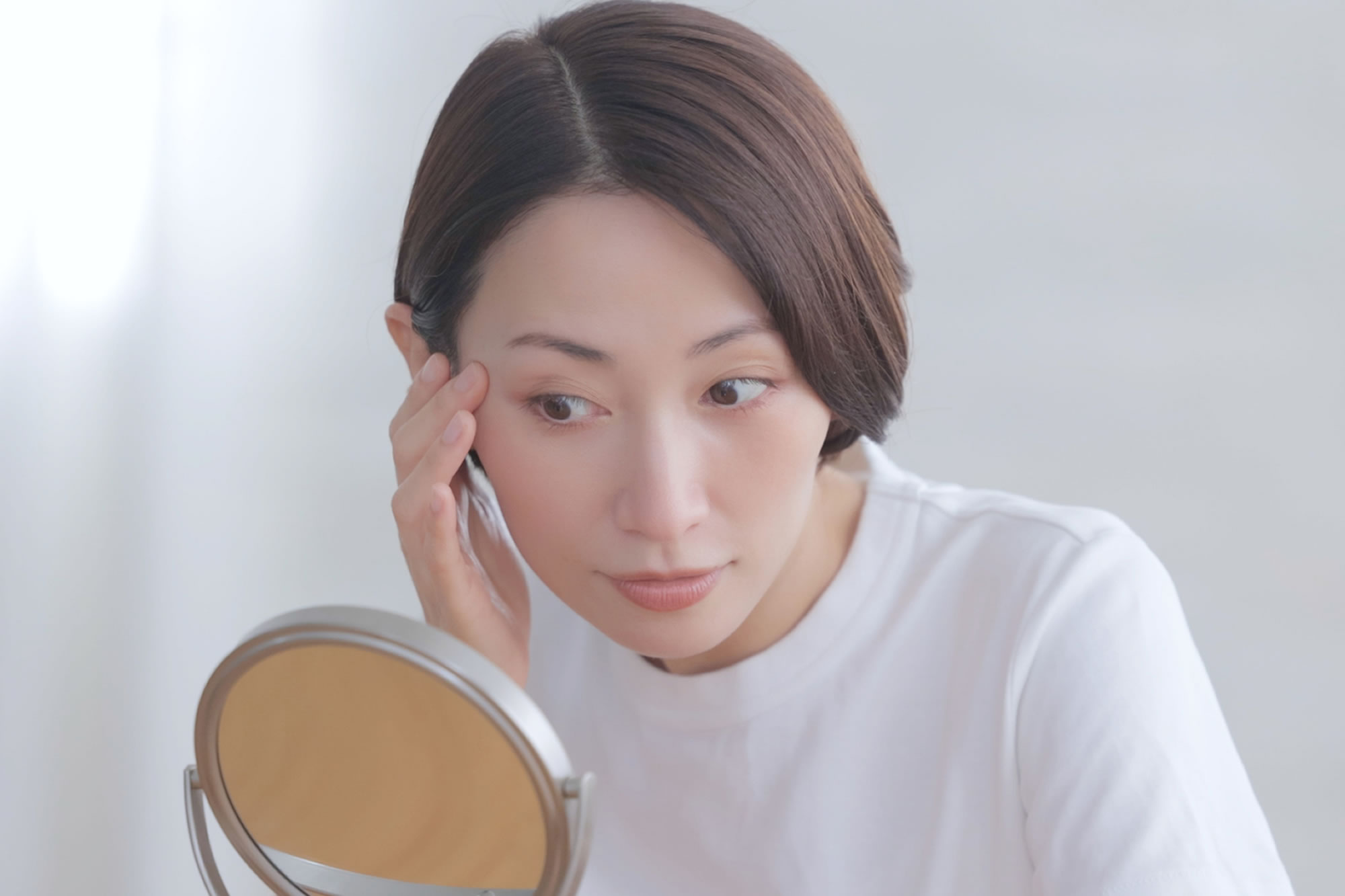 鏡を見てソバカスをきにしている女性