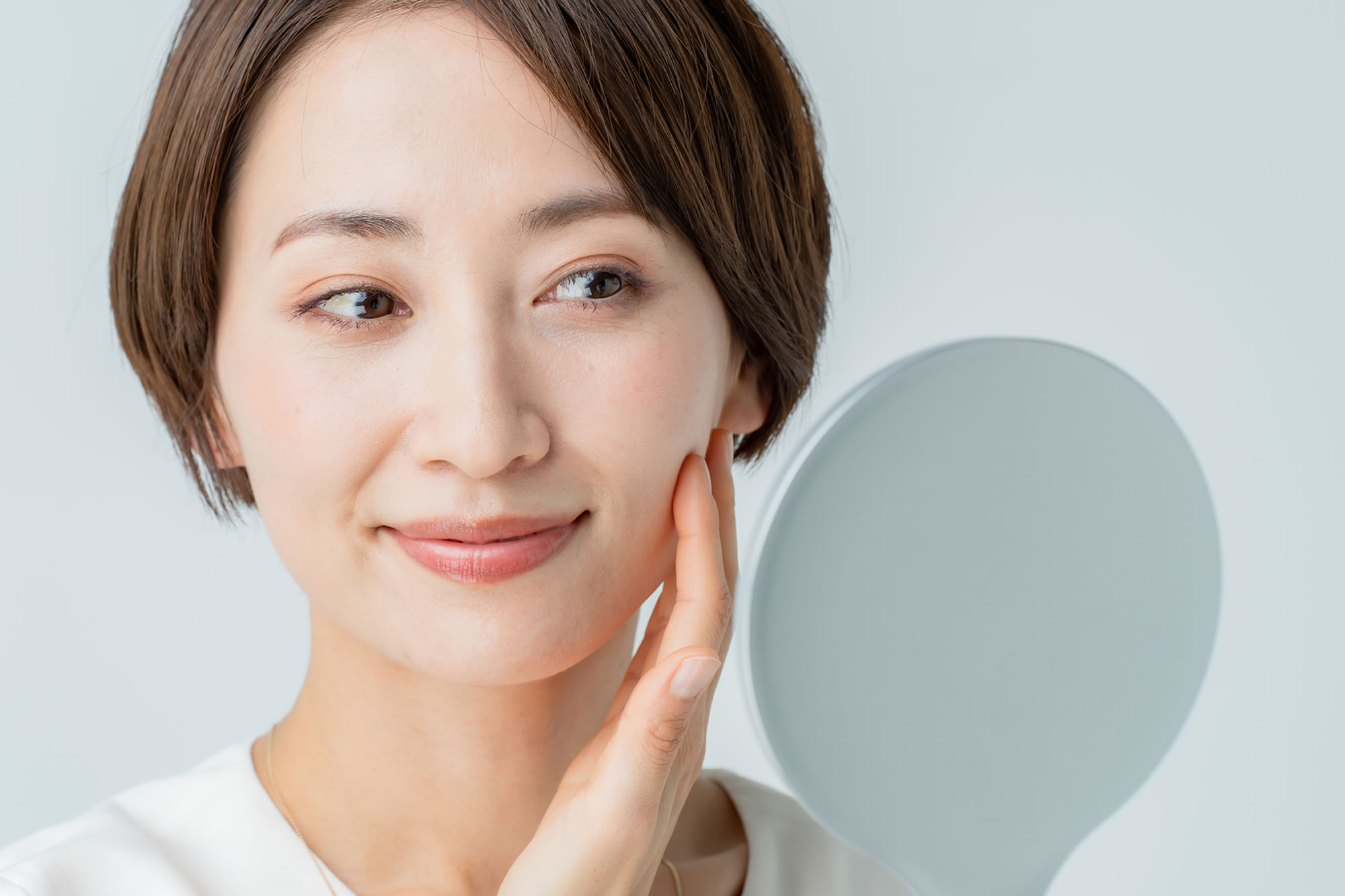 鏡を見て肌の色素沈着を気にする女性