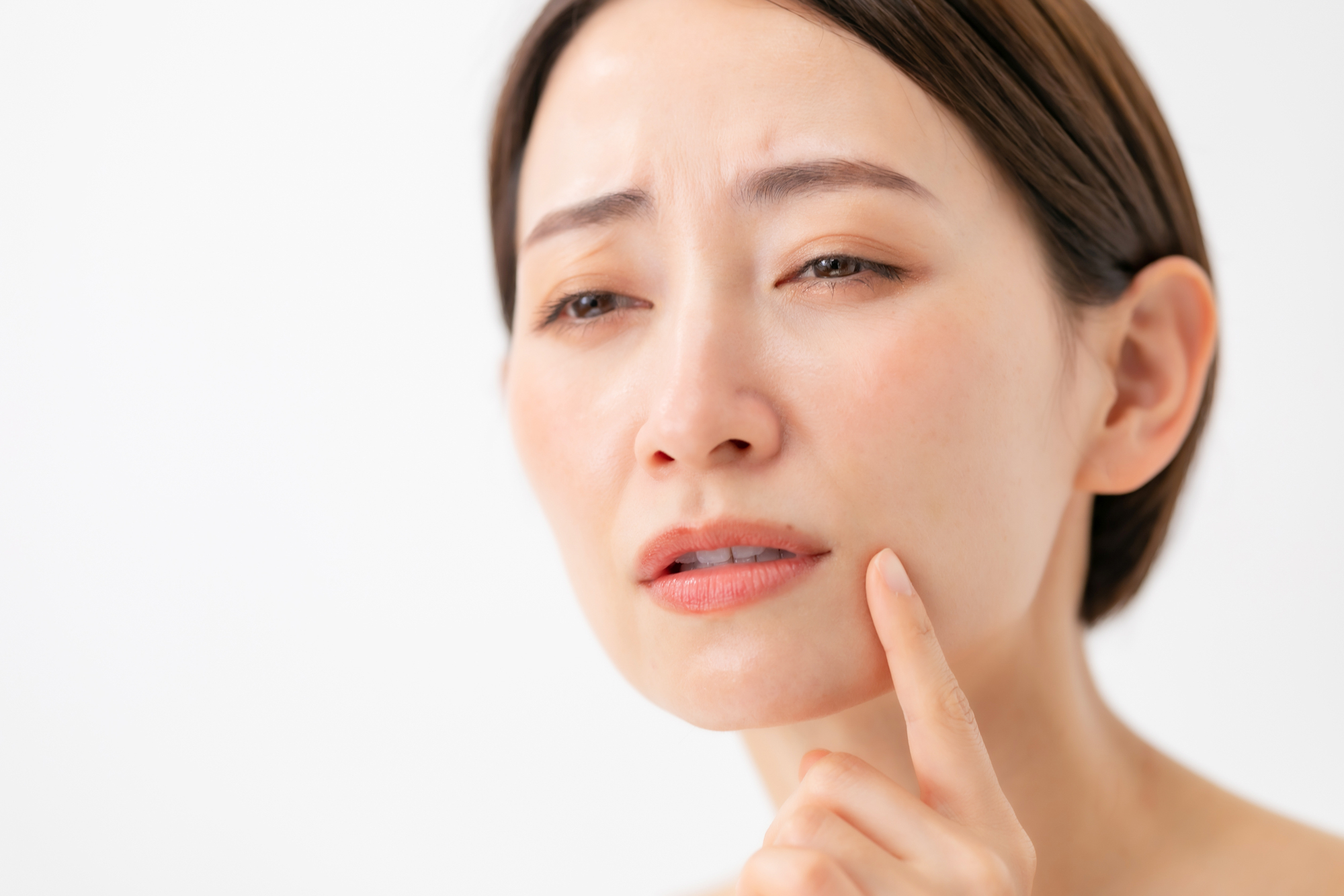 頬のしわを鏡で確認する女性
