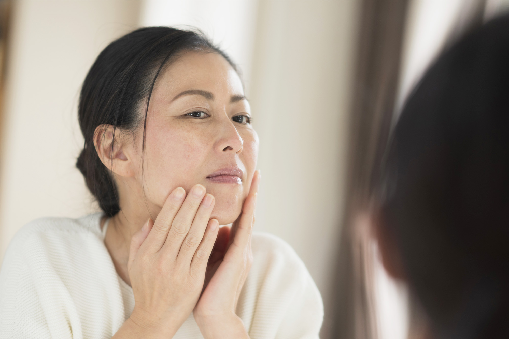 鏡を見てシワを気にする女性